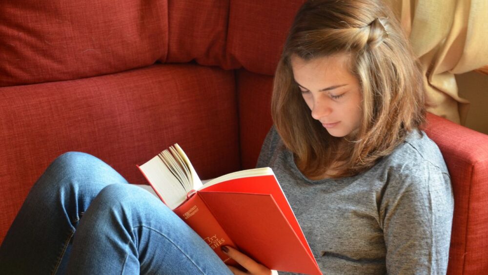 女性がソファーにすわってゆっくり本を読む